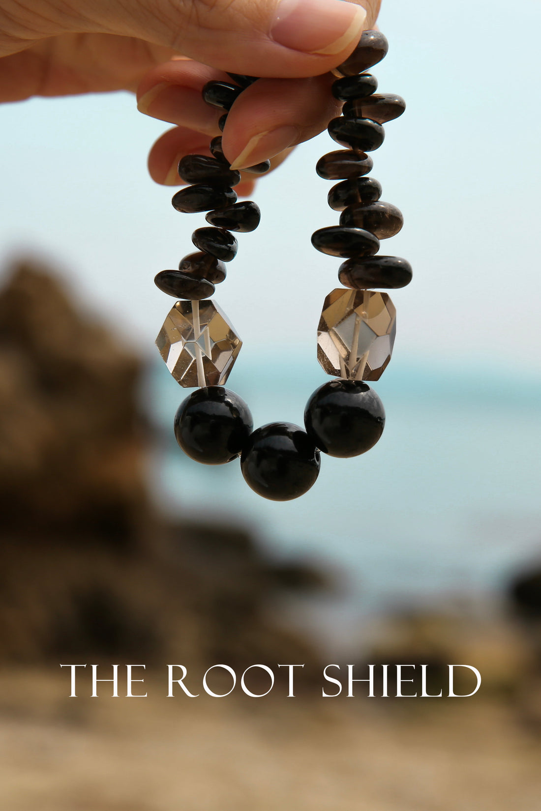 Obsidian and Smoky Quartz bracelet held outdoors against a natural landscape